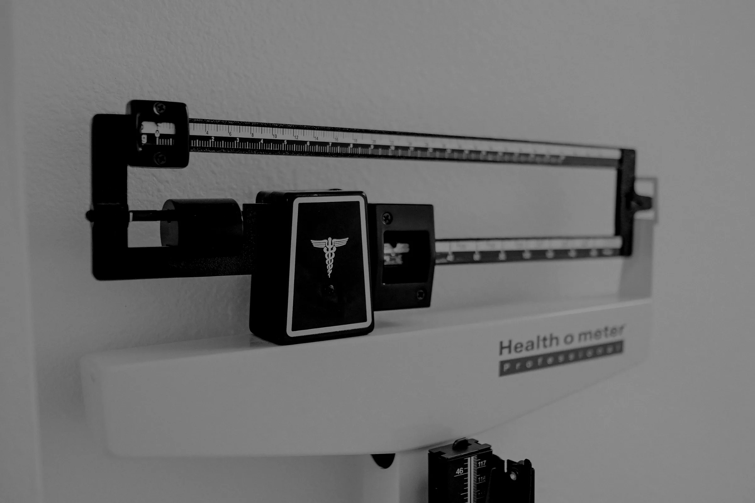 A professional balance-beam weighing scale against a plain wall.