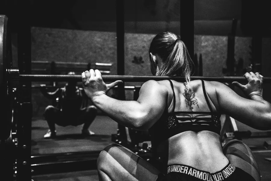 A lifter mid-squat under a loaded barbell in a rack.